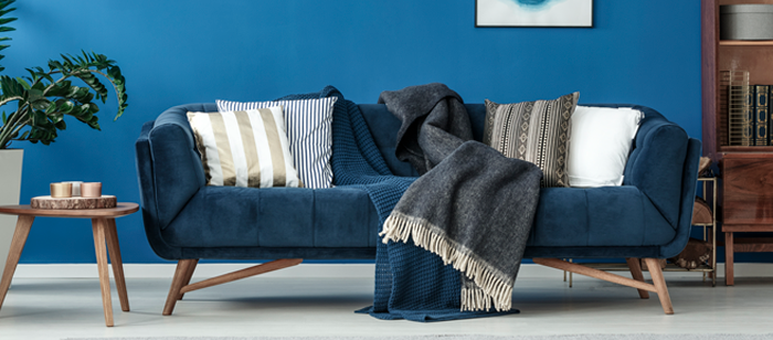 Exemplo de sofá combinando com almofadas, manta e mesinha de canto.